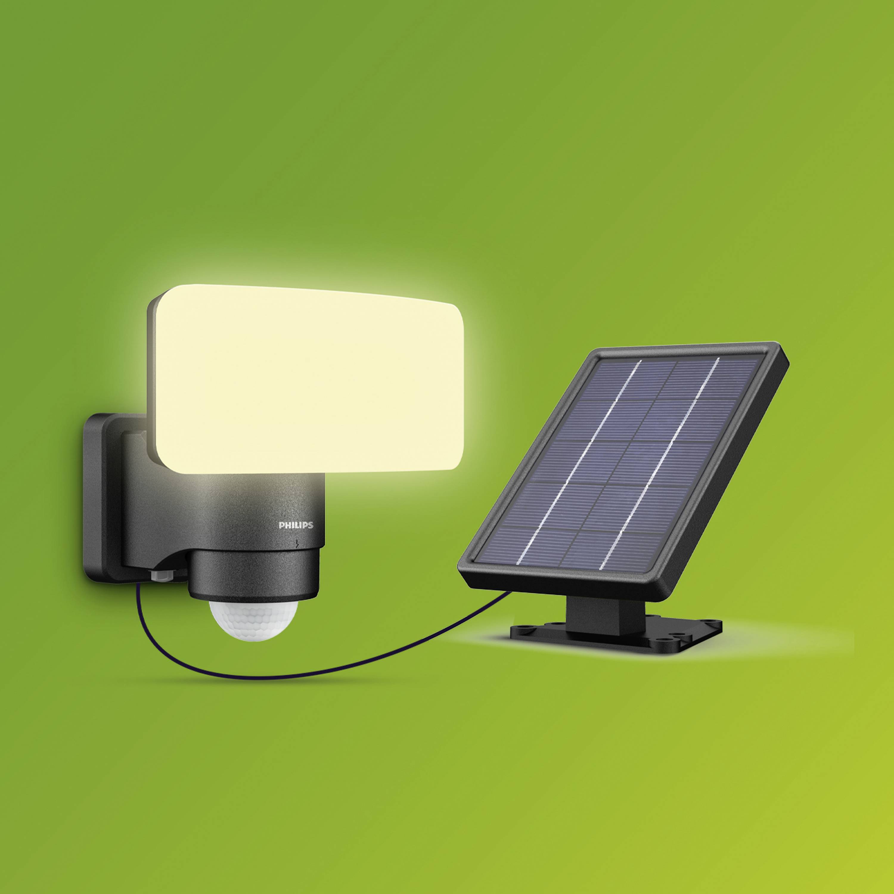 Lampe d'extérieur LED avec panneau solaire, illuminée, sur fond vert.