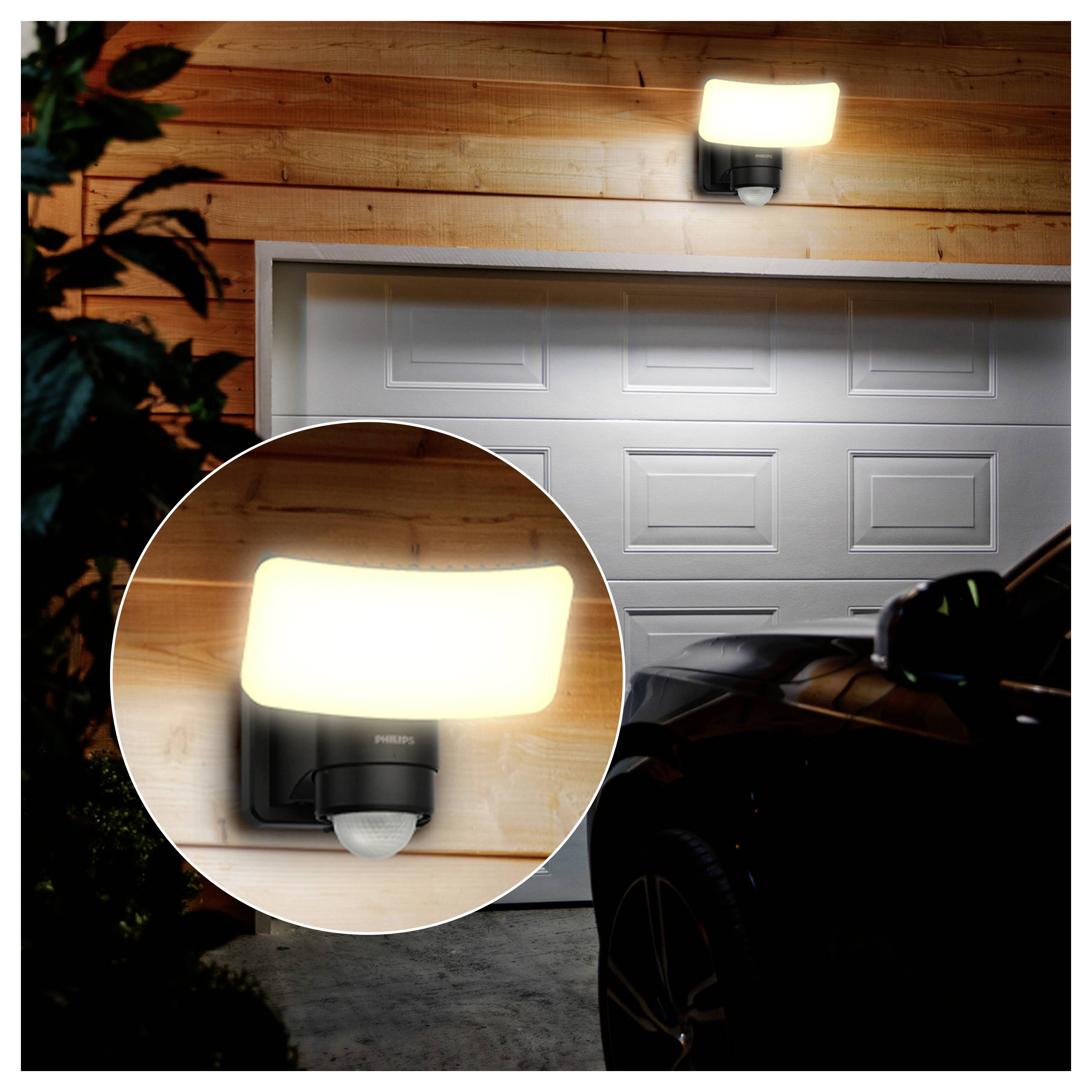 Lumière de capteur de mouvement montée sur mur extérieur brillant au-dessus d'une porte de garage la nuit, montrée avec un encadré rapproché du luminaire.