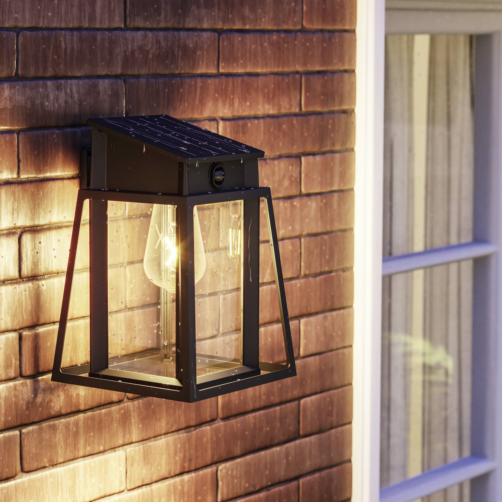 Lanterne murale avec ampoule illuminée près d'un mur de briques à côté d'une fenêtre. Éclairage électrique extérieur.