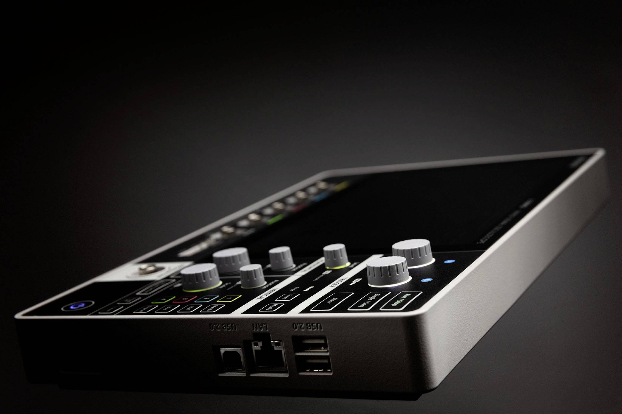 Une console de mixage avec plusieurs faders et boutons sur une surface sombre, utilisée pour le contrôle audio dans les studios ou lors d'événements.