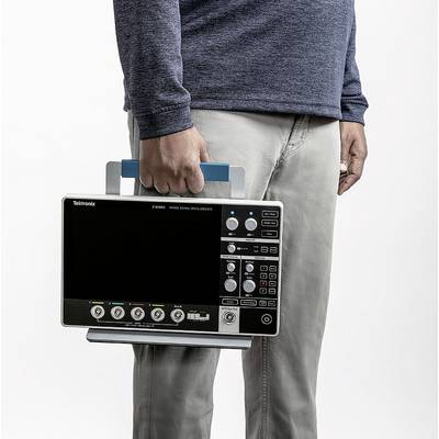 Une personne tient un oscilloscope portable par sa poignée. L'écran de l'oscilloscope n'affiche aucune donnée.
