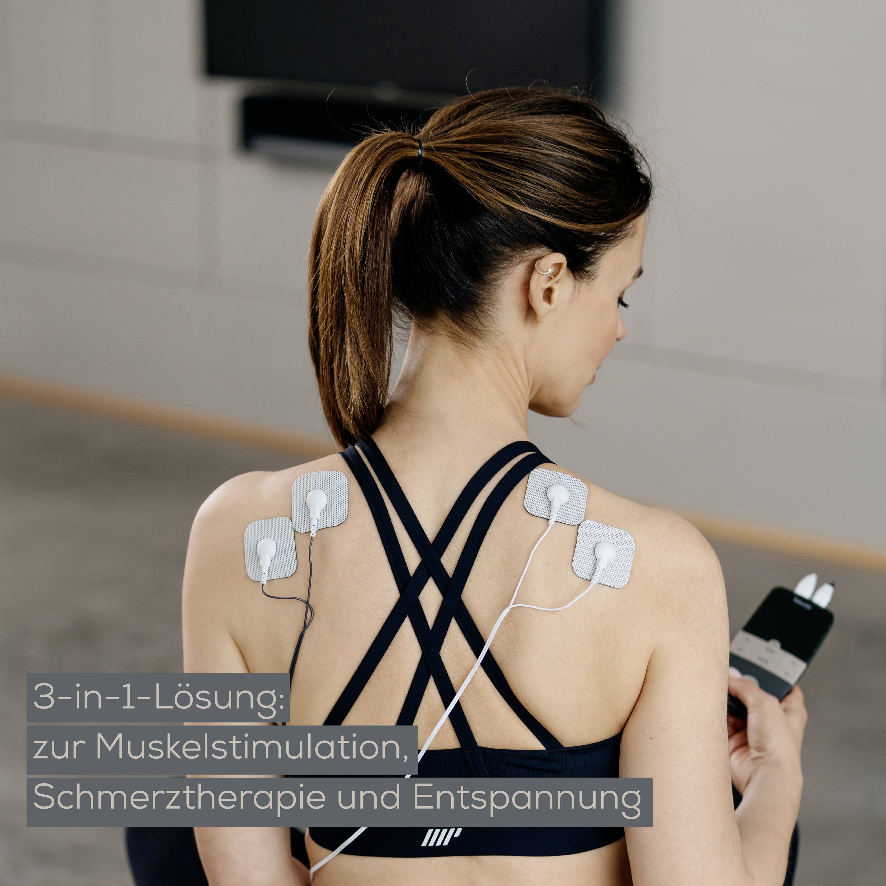 Une femme applique des patches adhésifs de stimulation musculaire sur son dos, tenant l'appareil de commande. Texte : « Solution 3-en-1 : stimulation musculaire, thérapie antidouleur, relaxation ».