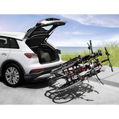 Une voiture blanche avec le coffre ouvert est garée sur la plage. Un porte-vélos avec deux vélos est monté à l'arrière.