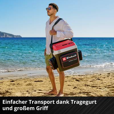 Un homme sur la plage porte une boîte avec une bandoulière. Il est inscrit 'Einhell' dessus. Texte : 'Transport facile grâce à la bandoulière et à la grande poignée'.