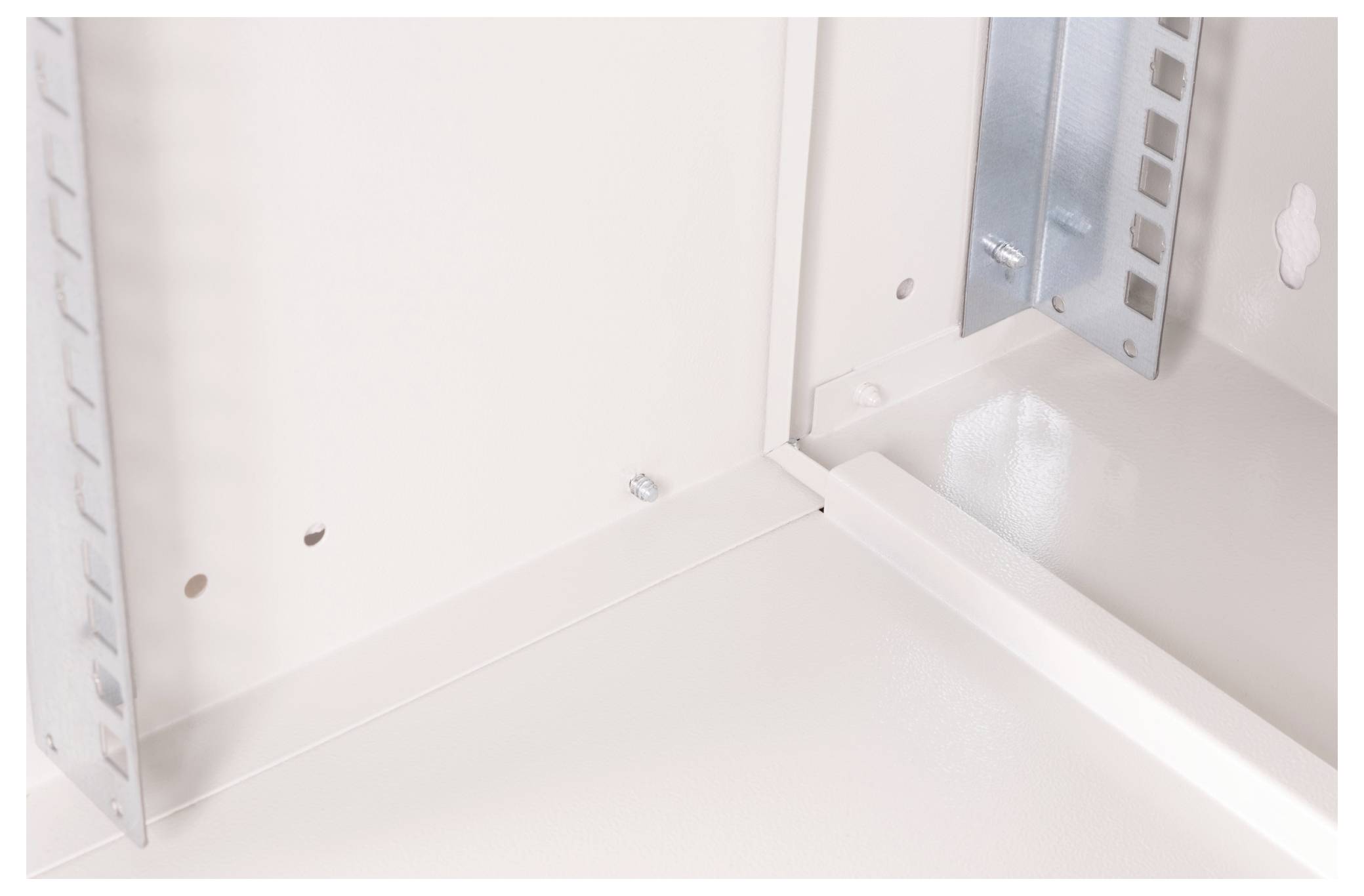 Angle intérieur d'une boîte métallique, montrant des panneaux alignés et des renforts d'angle. La lumière se reflète sur les surfaces blanches lisses et propres.