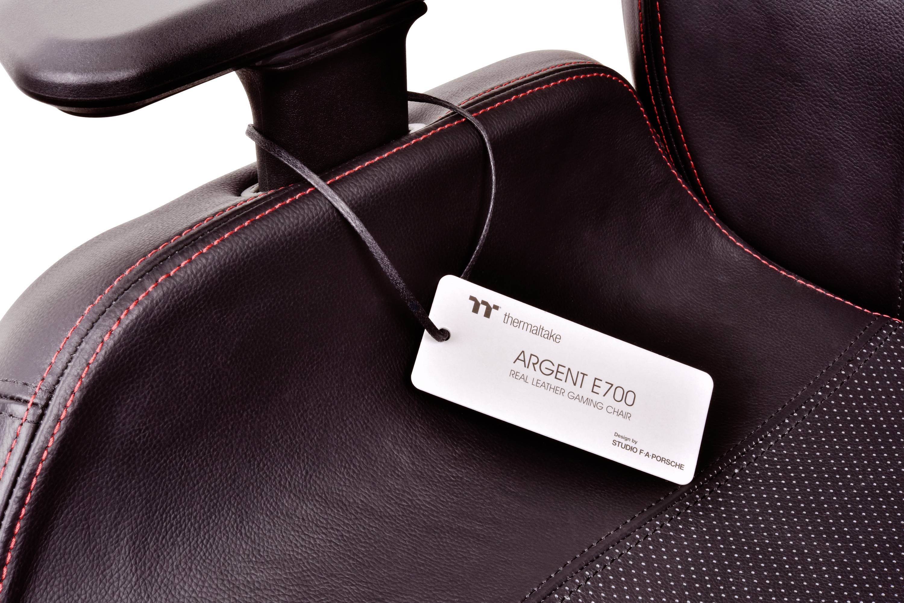 Chaise de gaming noire en cuir avec couture rouge. Une étiquette portant l'inscription 'ARGENT E700 Real Leather Gaming Chair' est fixée sur l'accoudoir.