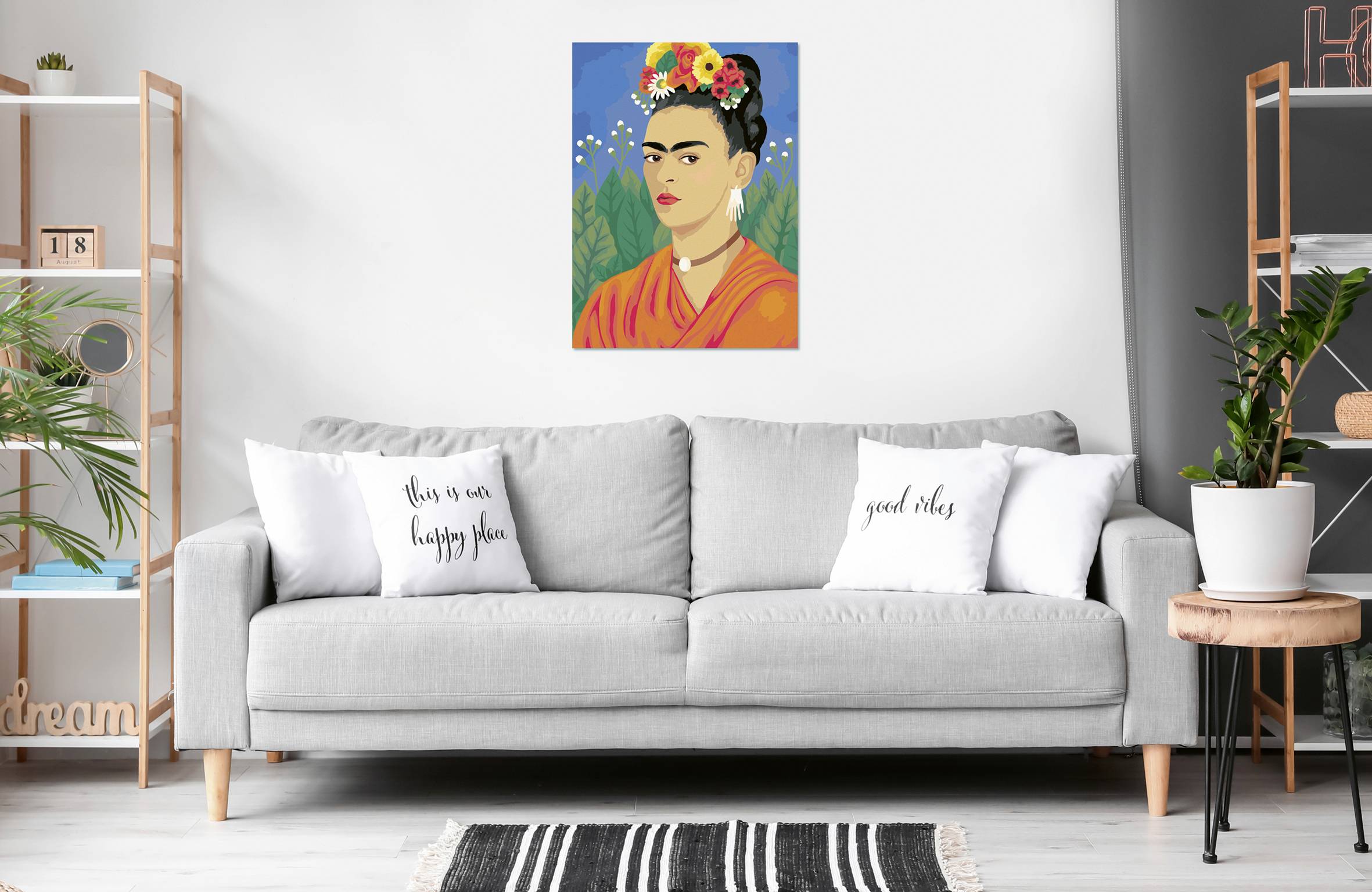 Un salon moderne avec un canapé gris sur lequel reposent deux coussins blancs. Un portrait coloré d'une femme est accroché au mur.