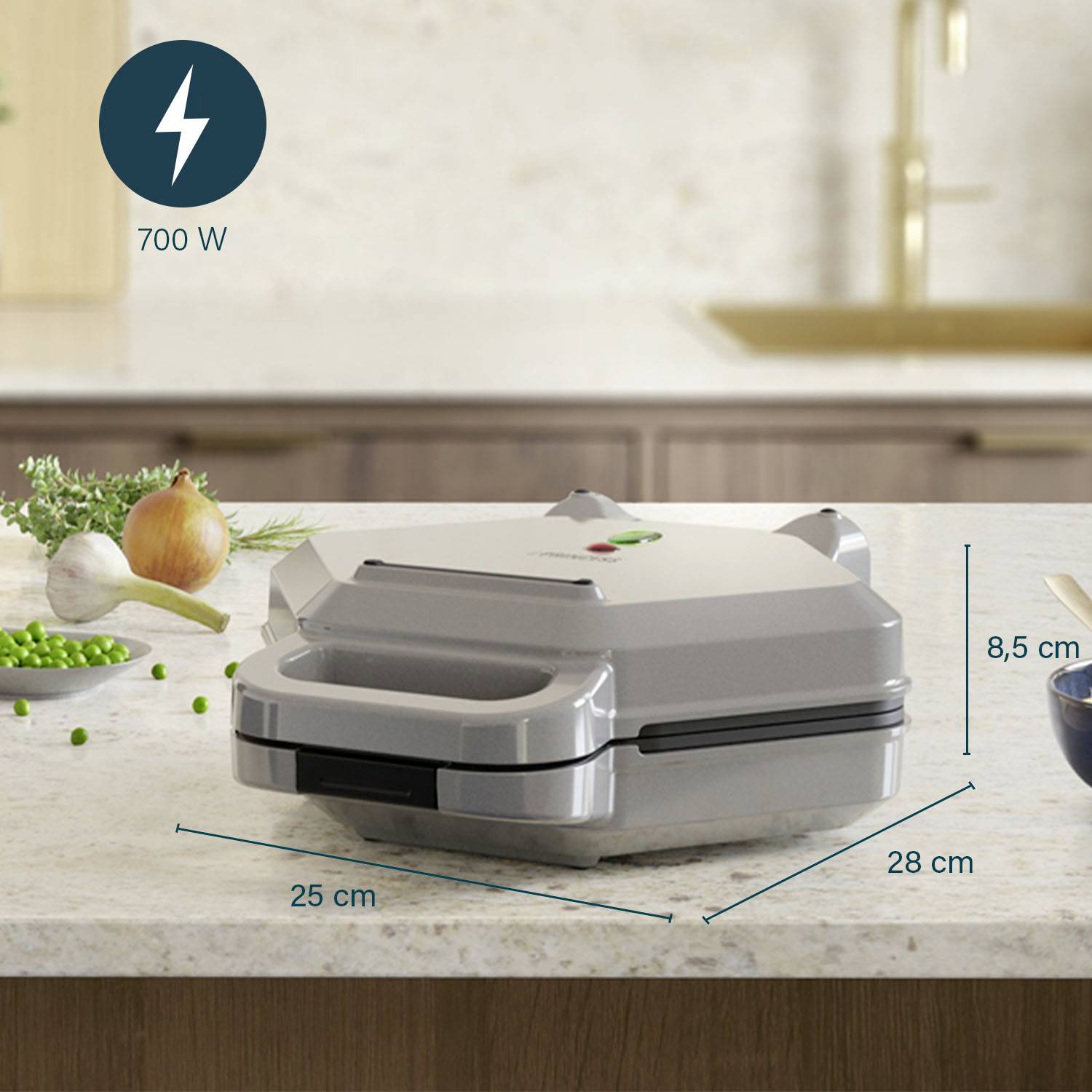 Un sandwich-maker argenté mesurant 25 cm x 28 cm x 8,5 cm est posé sur un plan de travail de cuisine. Puissance : 700 W.