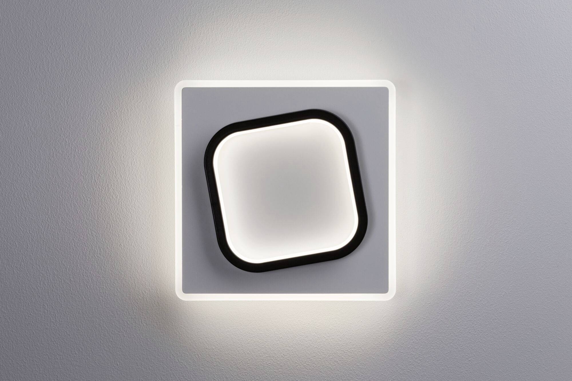 Une lampe carrée aux angles biseautés illumine doucement un mur et crée une ambiance moderne.