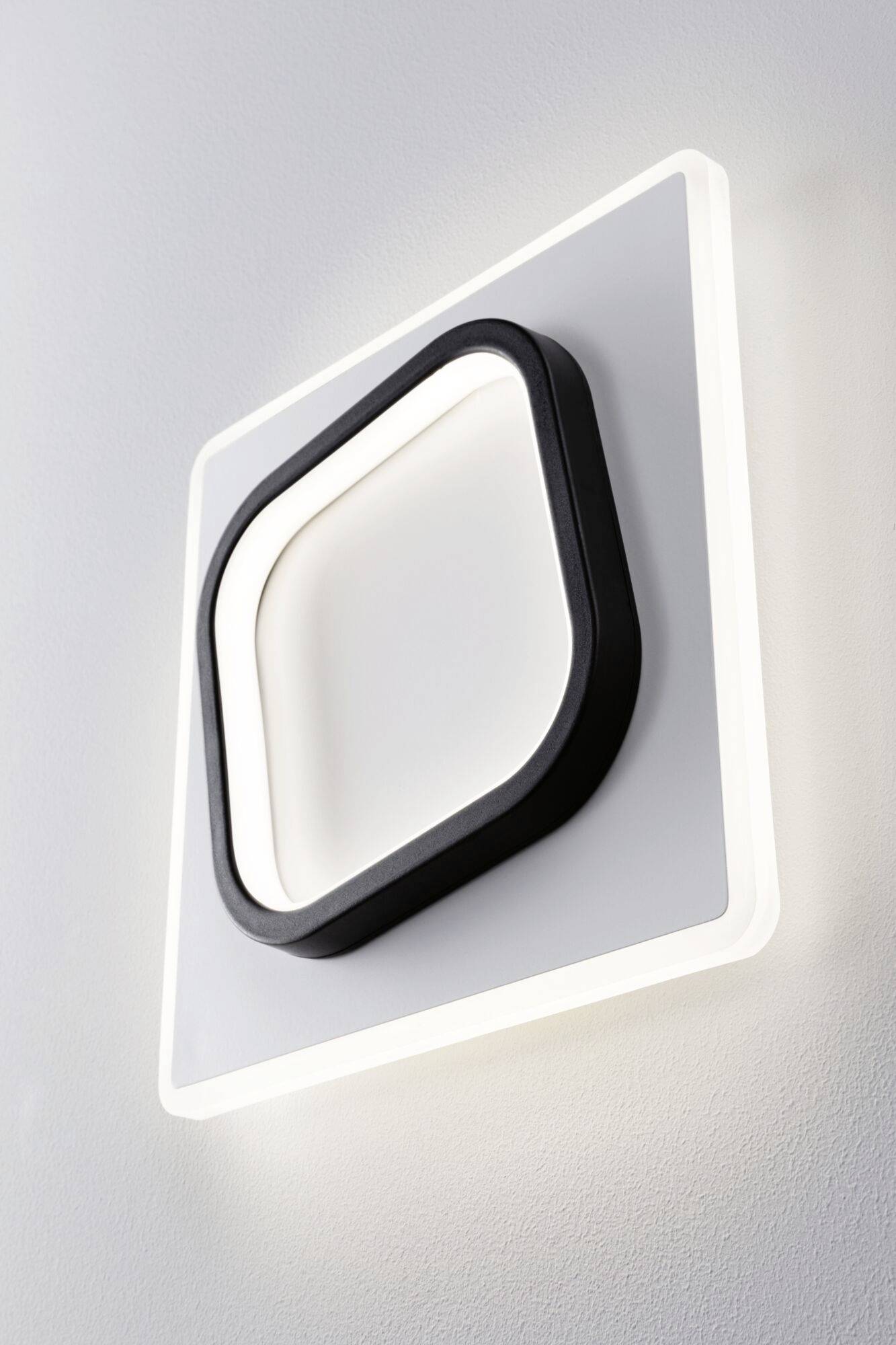 Applique murale LED au design carré et incurvé en noir et blanc. Elle diffuse une lumière douce et présente un aspect décoratif moderne.