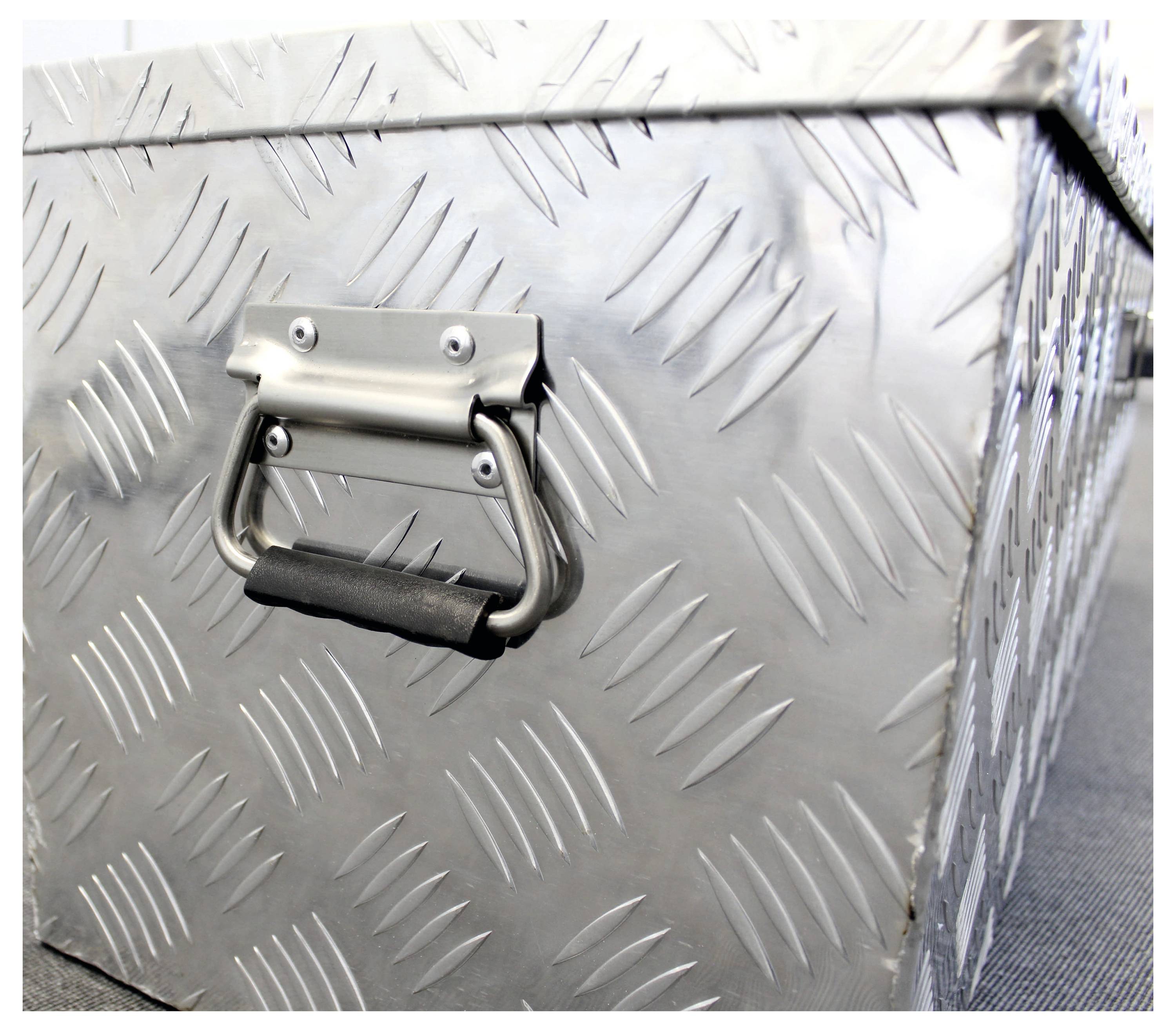 Boîte en aluminium argenté avec un motif losangé distinctif et une poignée robuste, sur un fond sombre.