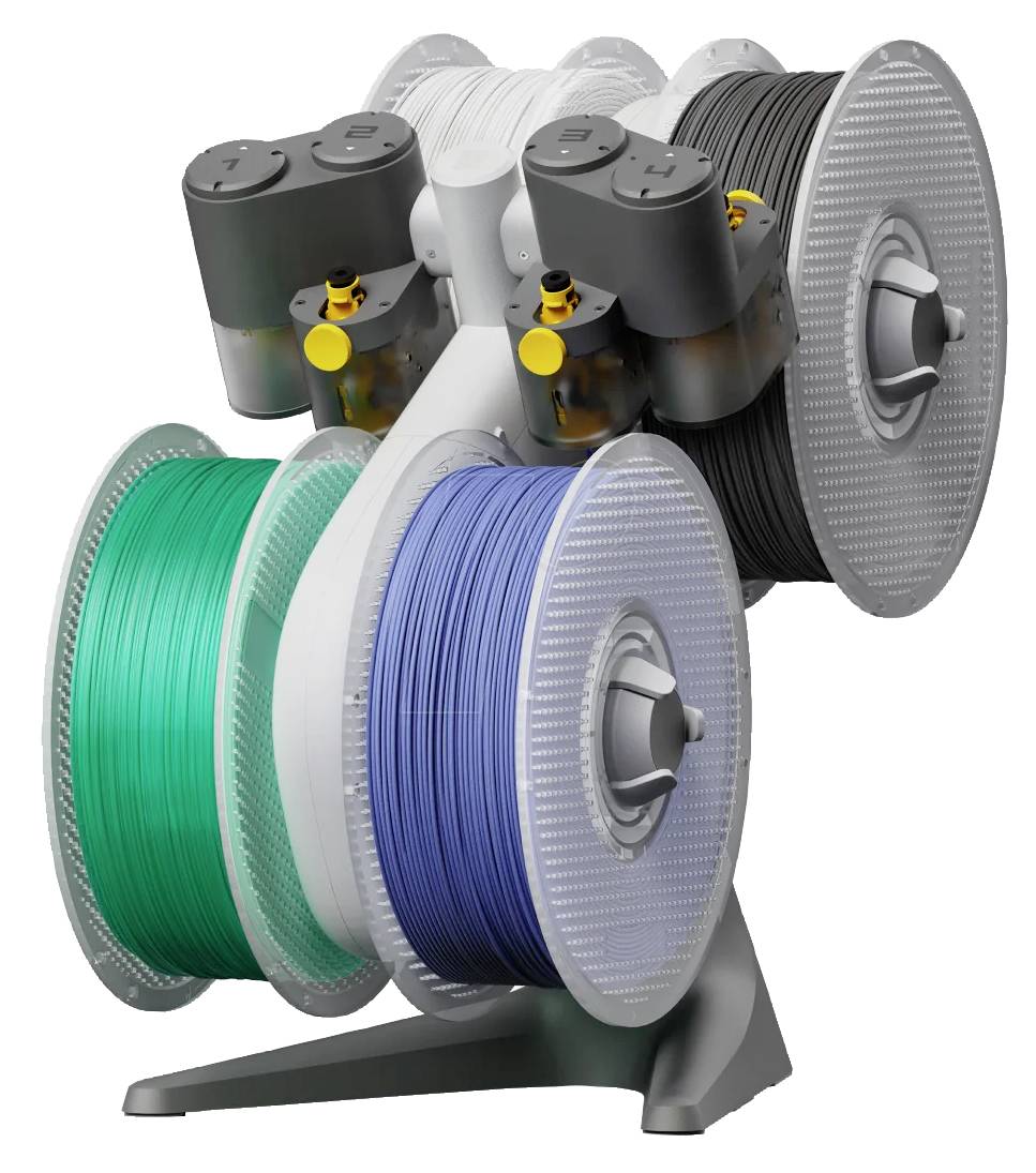 Plusieurs grandes bobines avec des filaments colorés (vert, bleu, blanc, noir) sont montées sur un support, prêtes à être utilisées.