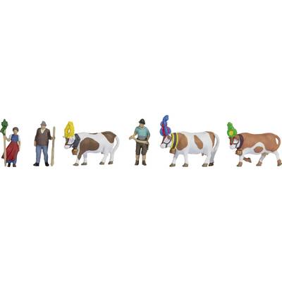 Figurines miniatures de deux personnes en tenue traditionnelle accompagnées de trois vaches portant des coiffes colorées et des sonnailles.