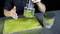 Une personne démontre l'utilisation d'un applicateur d'herbe sur une plaque de maquette. Deux dispositifs avec des fibres d'herbe sont visibles.