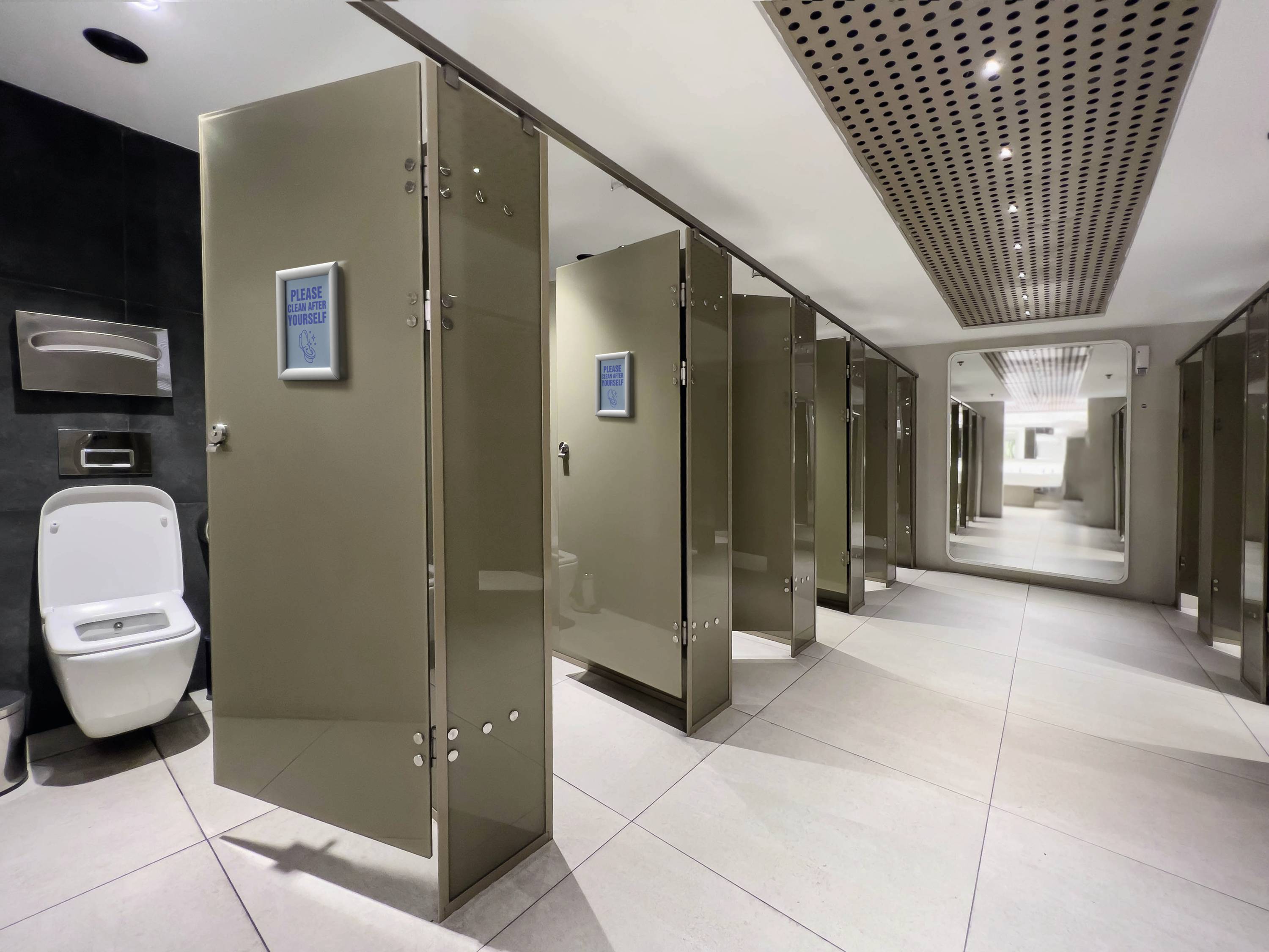 Une salle de toilettes moderne et propre avec plusieurs cabines et des portes ouvertes ; un espace lavabos en arrière-plan.