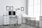 Cabinet médical moderne avec bureau, ordinateur, documents affichés au mur et table d'examen à côté de grandes fenêtres.