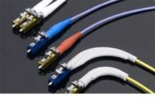 Six câbles à fibre optique différents avec des connecteurs colorés sur un fond sombre, montrant des variations dans le design et la fonction.