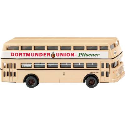 Un bus à impériale de couleur crème avec une publicité pour 'Dortmunder Union Pilsener' sur le côté, est stationné sur une surface blanche.
