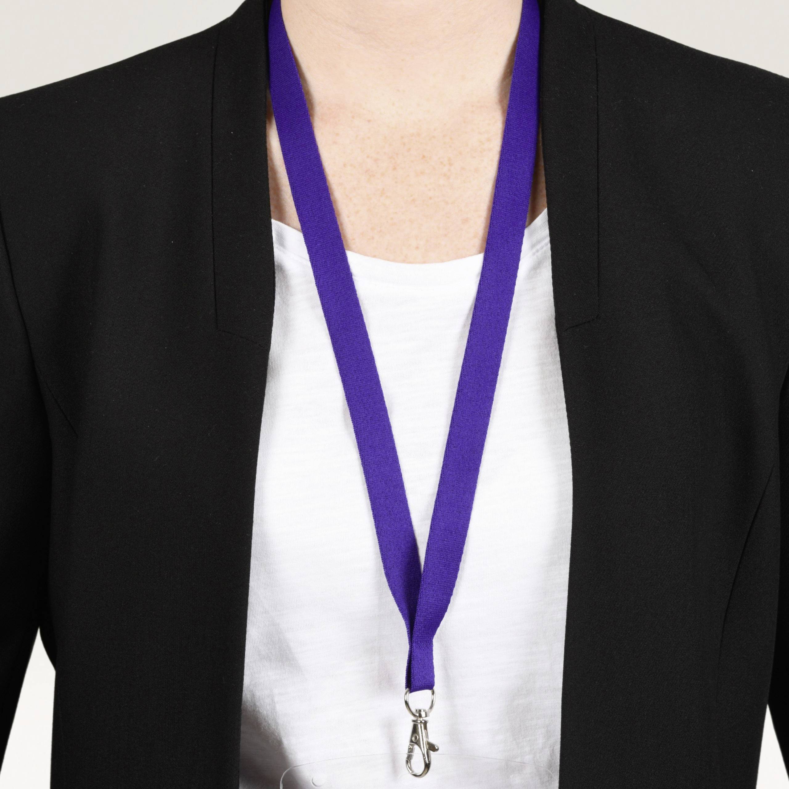 Une personne portant une chemise blanche et un costume noir porte une médaille violette autour du cou. Seule la partie supérieure du corps est visible.