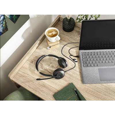 Un ordinateur portable sur une table en bois, avec un casque connecté, une tasse de café et un carnet de notes, illustre un environnement de travail ou d'apprentissage à domicile.