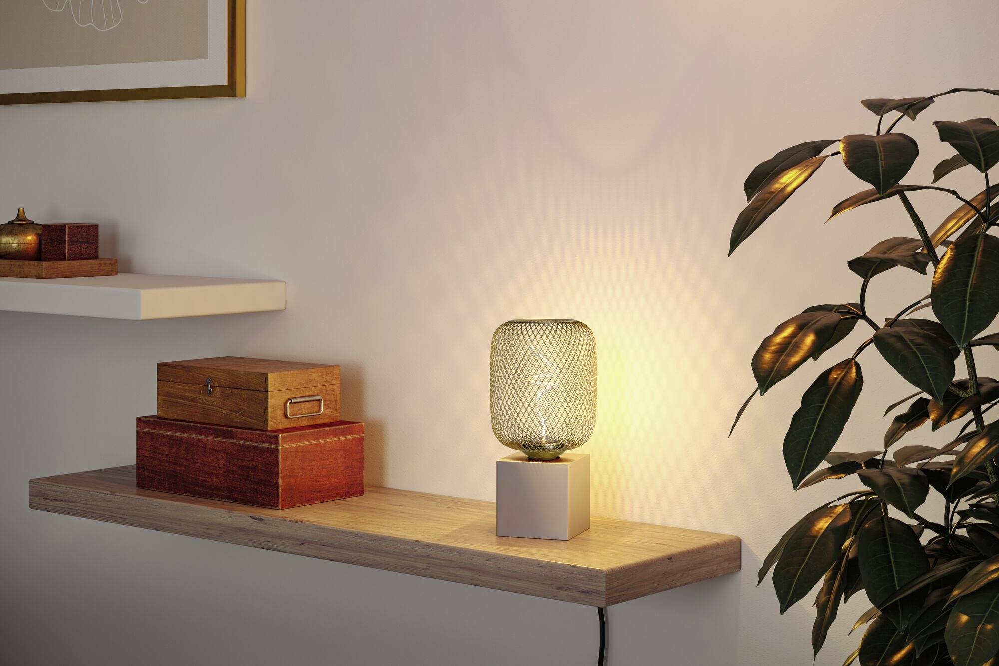 Une lampe de table éclairée est posée sur une étagère flottante en bois, à côté de boîtes décoratives, avec une plante en arrière-plan.