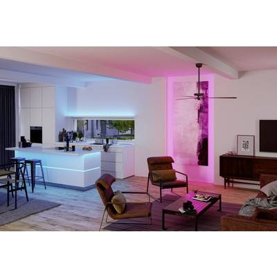 Un salon moderne avec une cuisine ouverte, éclairé par une lumière bleue et rose. Plancher en bois, fauteuil, table basse et tabourets de bar.