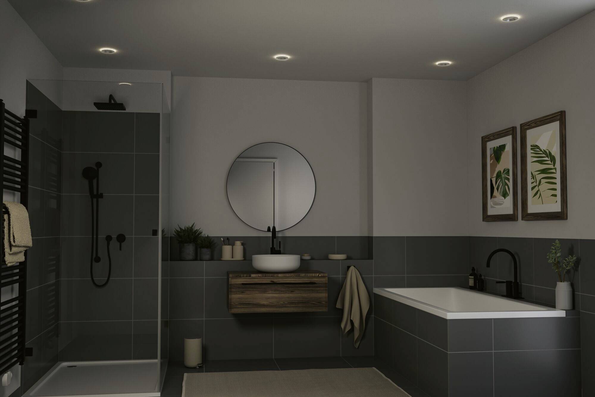 Salle de bain moderne avec des carreaux sombres, miroir rond au-dessus du lavabo suspendu, douche à gauche, baignoire à droite et deux tableaux verts au mur.