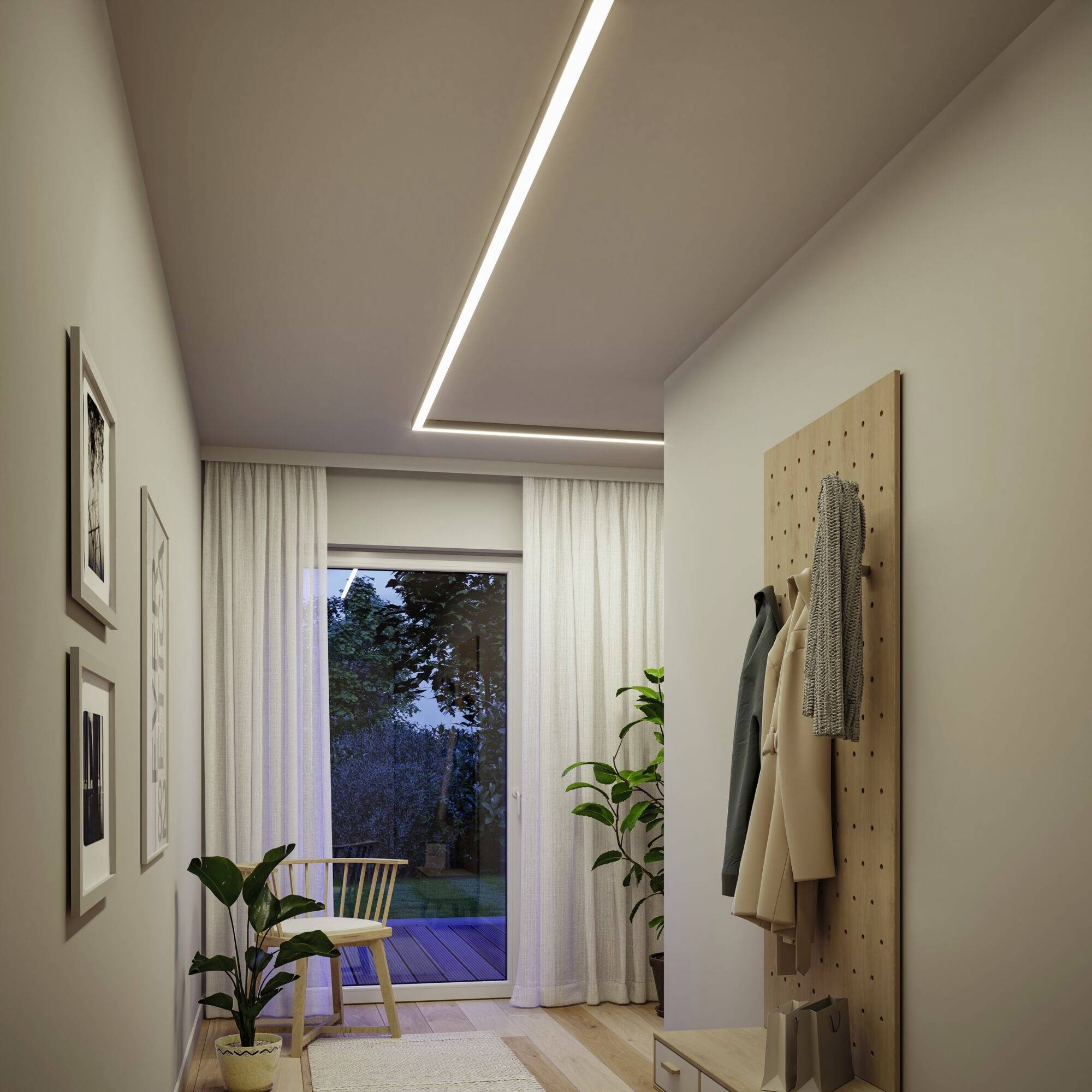 Couloir avec un éclairage mural élégant et des plantes, une fenêtre avec un rideau menant à une terrasse ; à côté, un portant en bois avec des vêtements.