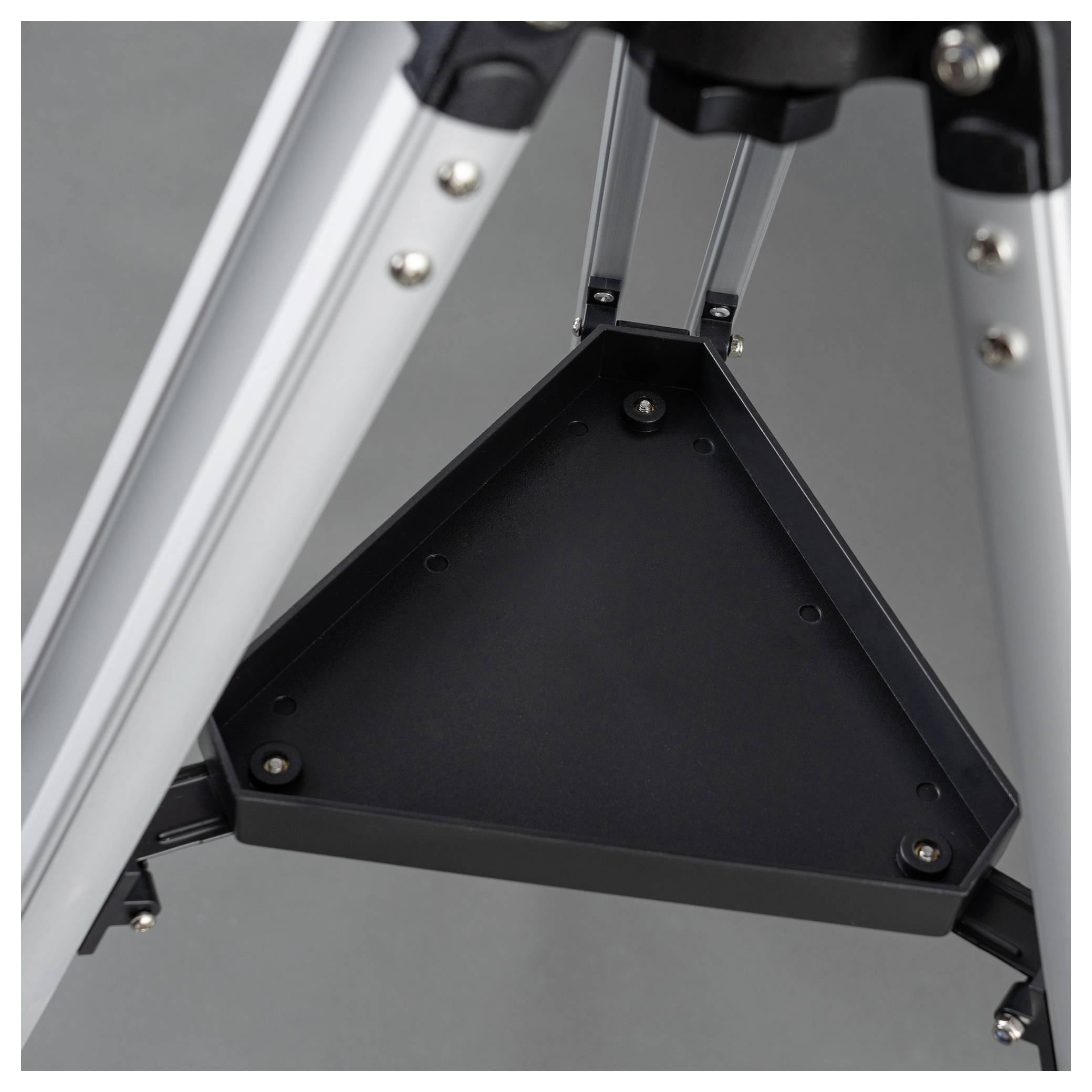 Petite surface triangulaire sur un pied de trépied, conçue pour ranger de petits objets ou outils pendant l'utilisation du trépied.