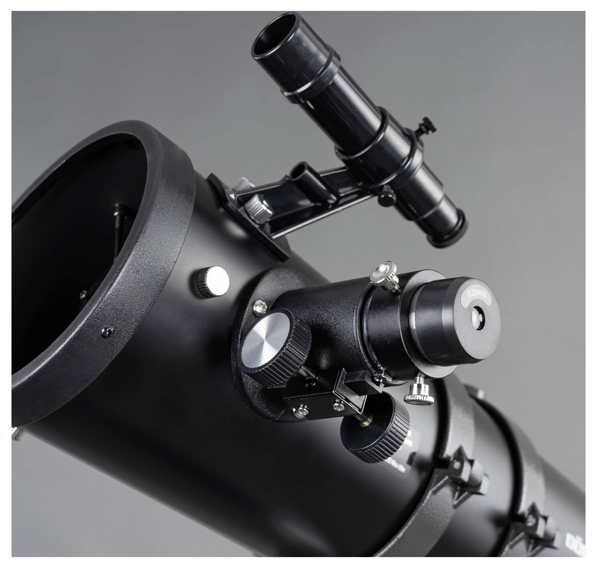 Un télescope noir avec un système de mise au point et un chercheur, pointé vers le ciel, sur un fond gris.