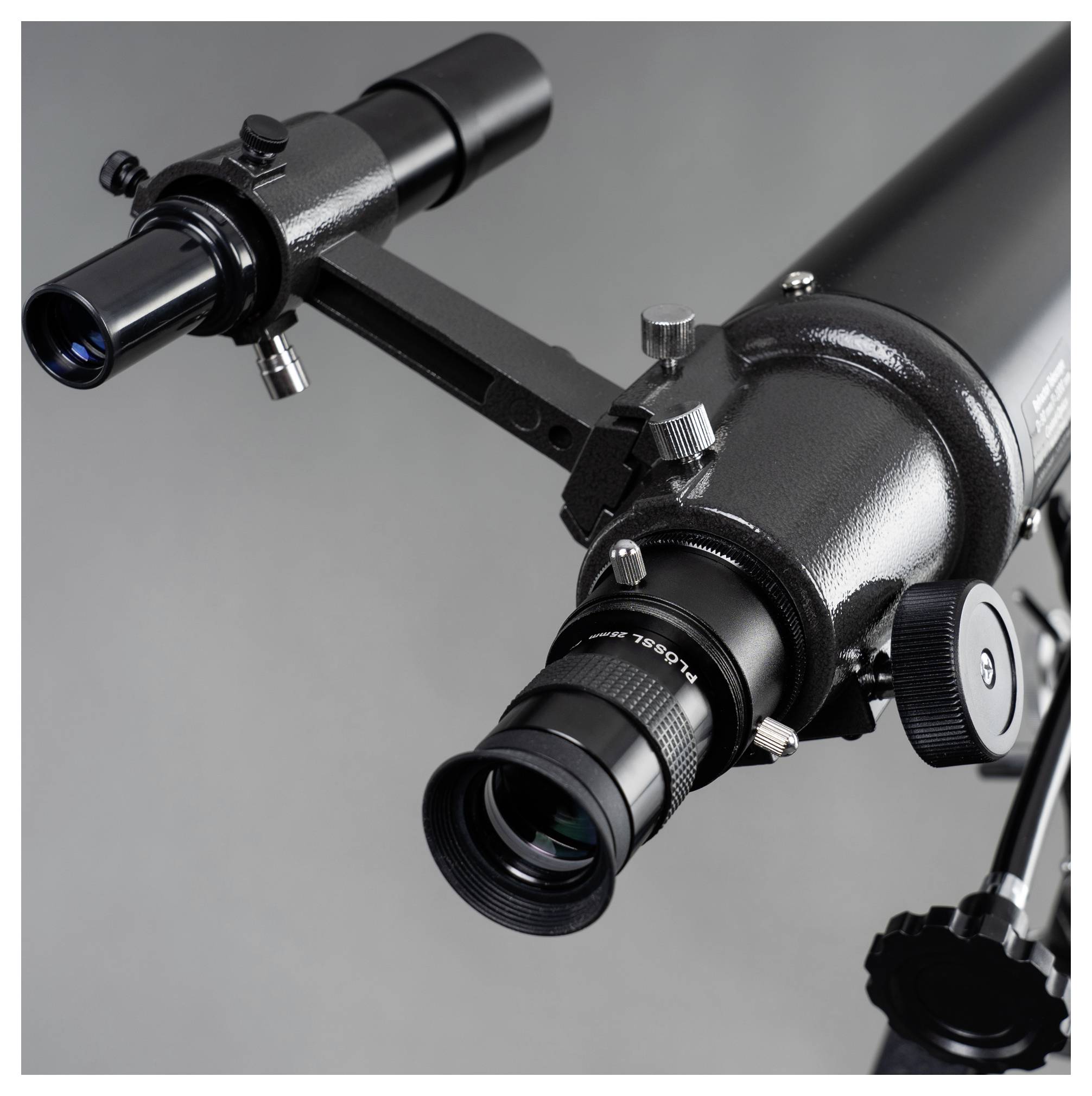 Un télescope noir avec des vis de réglage et un oculaire, monté sur un trépied.