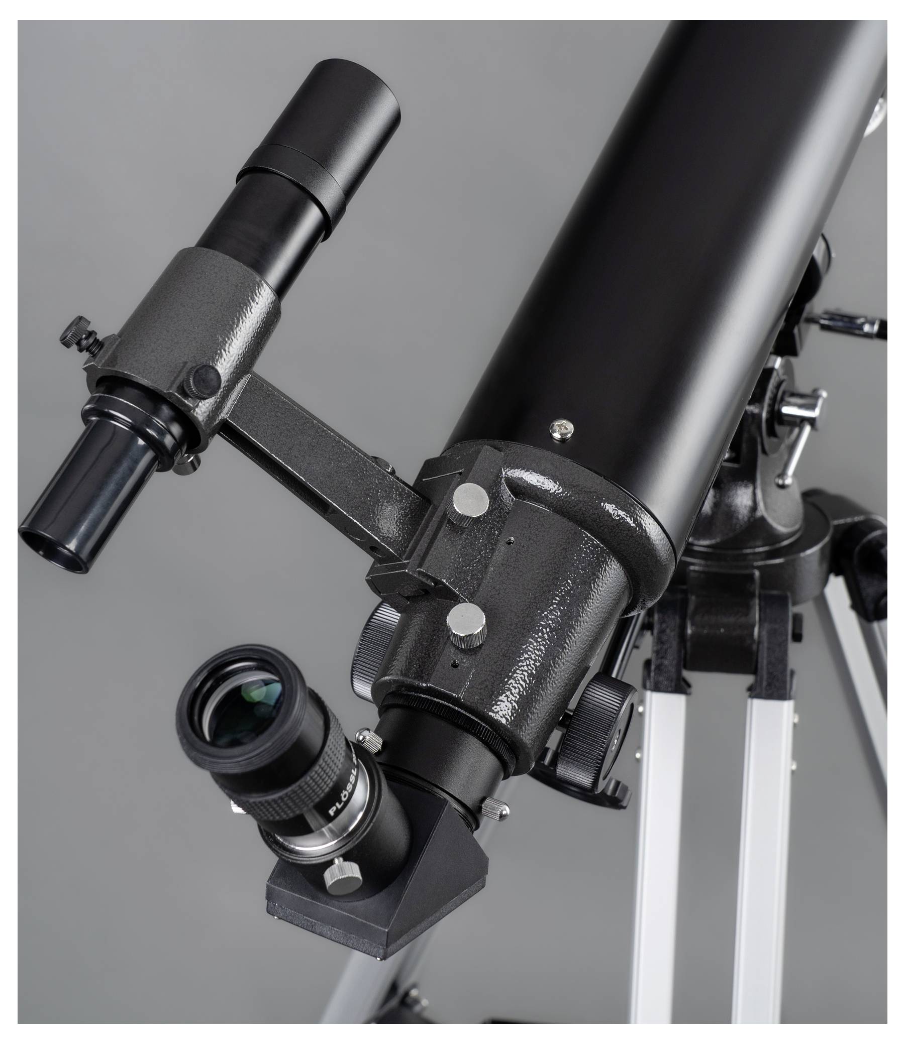 Un télescope noir avec plusieurs oculaires sur un trépied, prêt à observer le ciel.