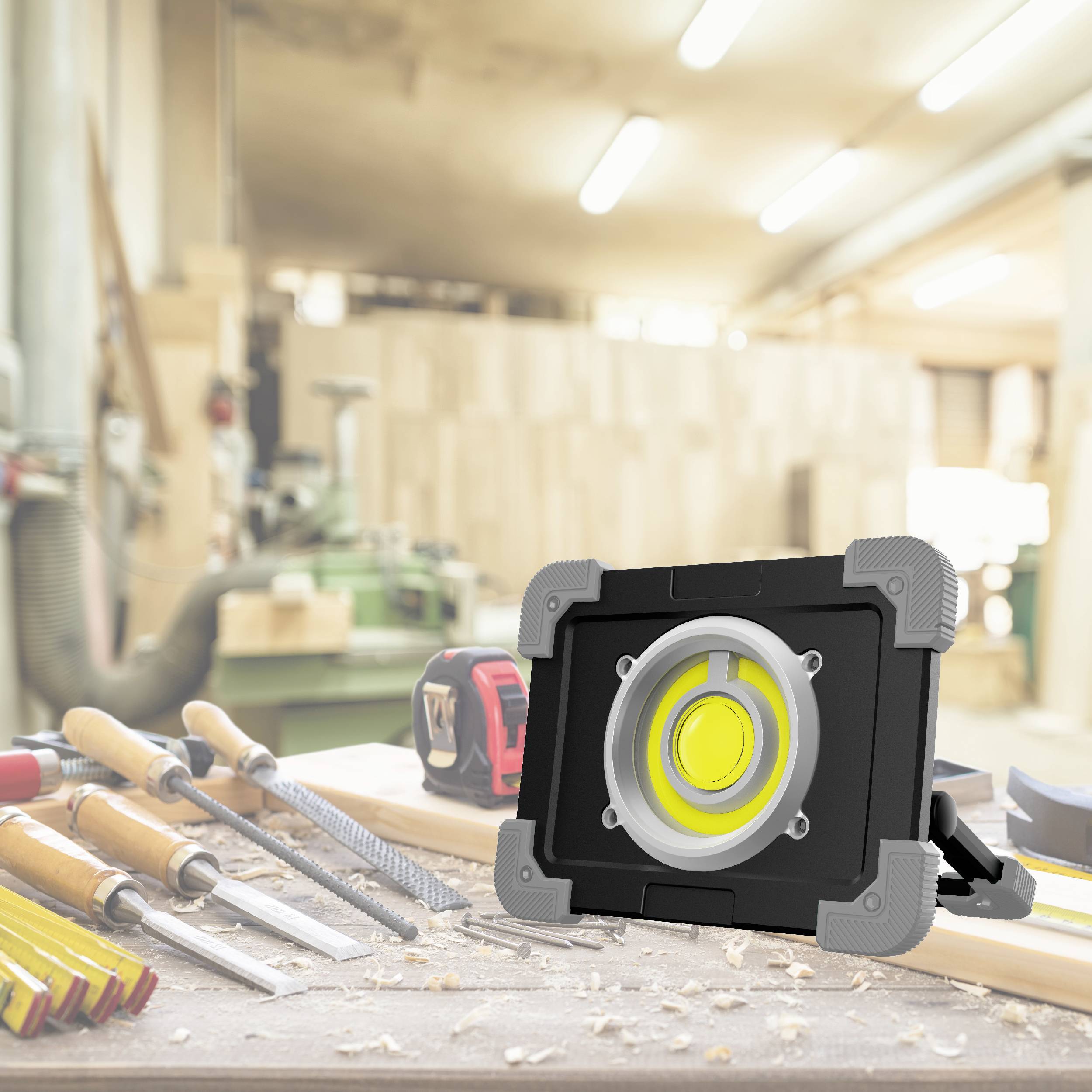 Établi d'atelier avec un projecteur LED à l'avant-plan, entouré de divers outils à main.