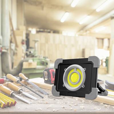Établi d'atelier avec un projecteur LED à l'avant-plan, entouré de divers outils à main.