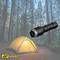 Tente dans la forêt la nuit avec une lampe de poche allumée au premier plan, suggérant une aventure de camping et une solution d'éclairage.