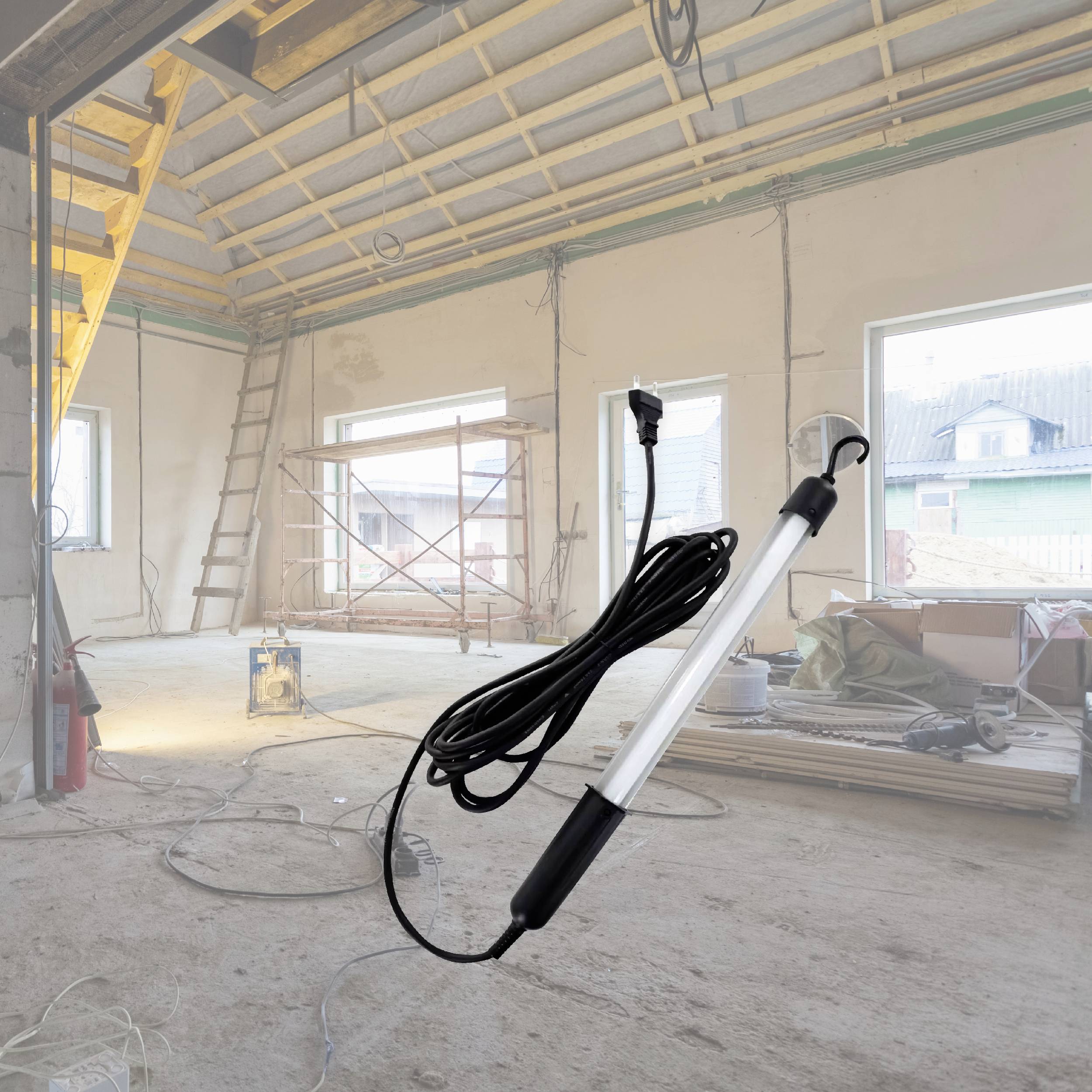 'Un chantier vide avec de grandes fenêtres. Une lampe de travail avec son câble est représentée de manière proéminente au premier plan.'