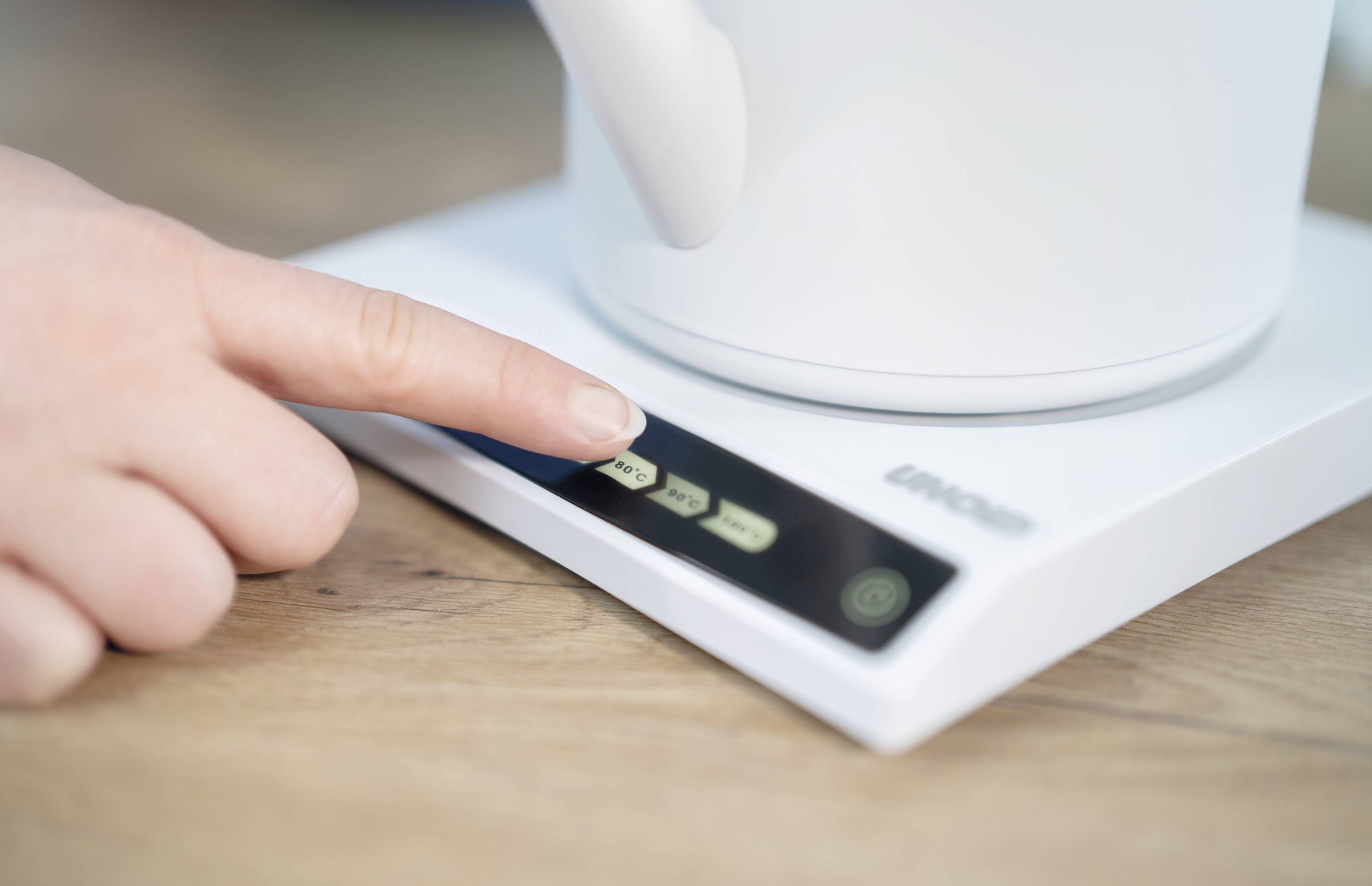 Un doigt appuie sur la touche d'un élément de commande numérique d'un appareil de cuisine, probablement pour un réglage ou une activation.