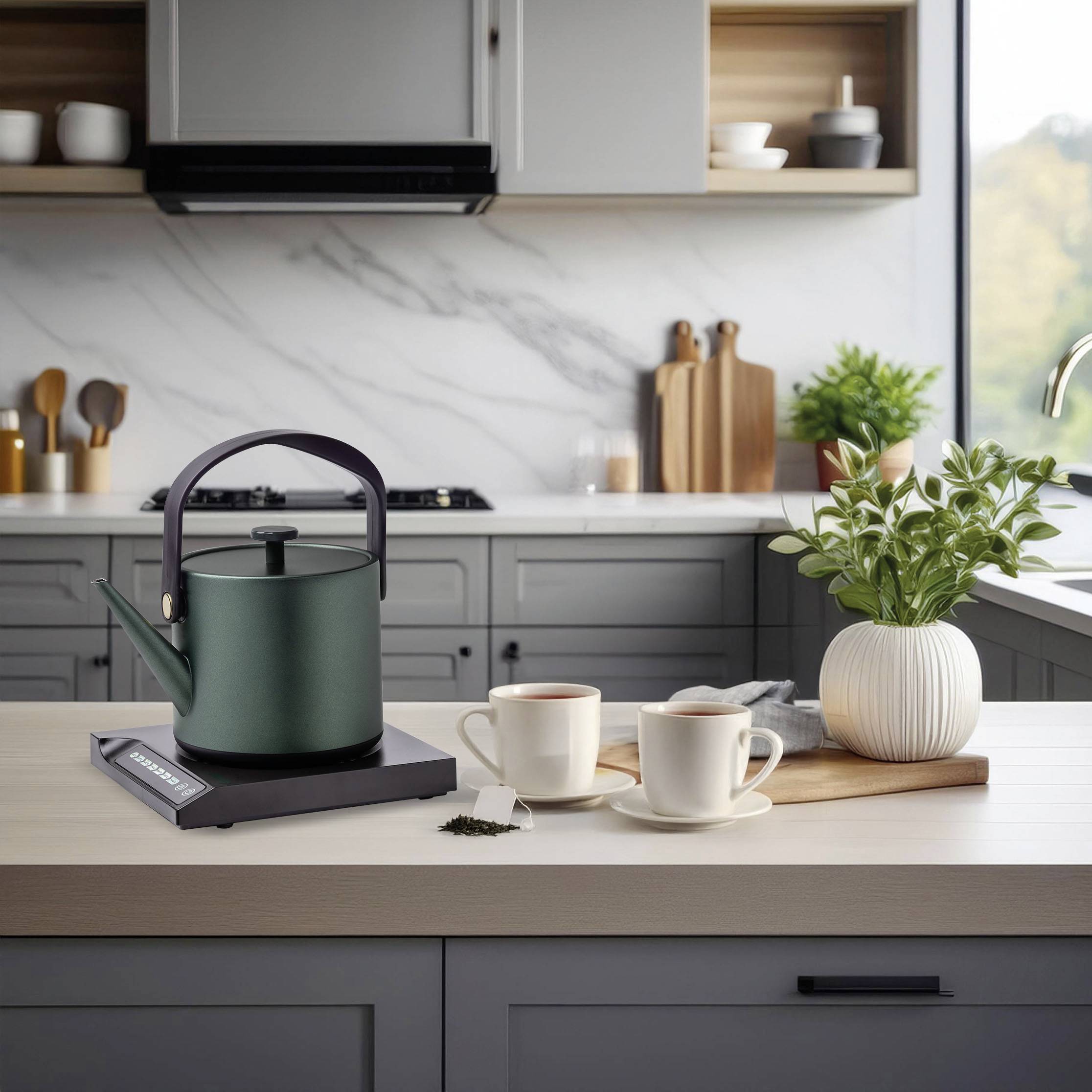 La cuisine montre une bouilloire verte sur un plan de travail avec deux tasses de thé. En arrière-plan, on peut voir des étagères et des plantes.