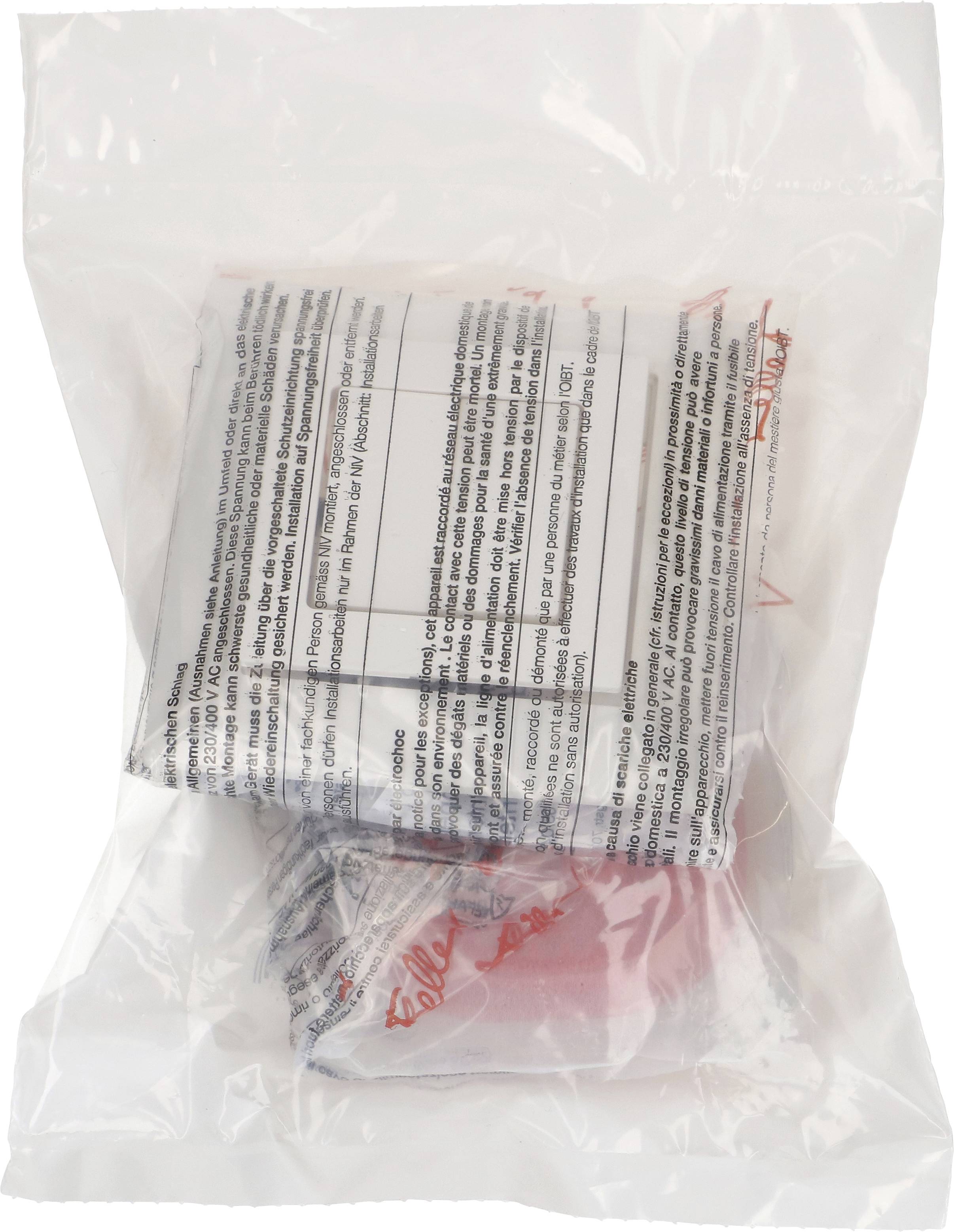 Un sac en plastique transparent contient un papier plié et un petit objet rouge. Le texte sur le papier est difficile à déchiffrer.