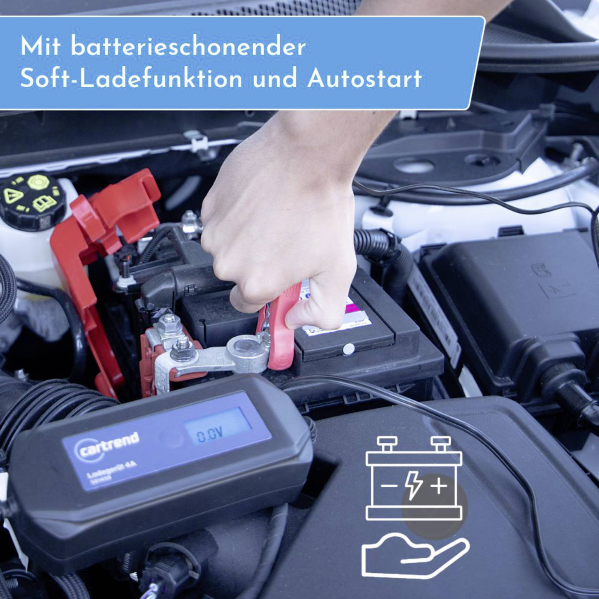 Une main utilise un chargeur pour connecter une batterie de voiture, portant l'inscription 'Avec fonction de charge douce ménageant la batterie et démarrage automatique'.