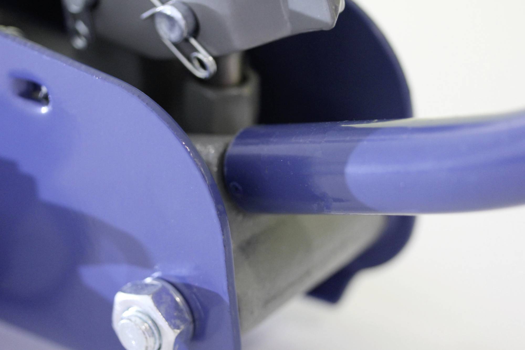 Pièce mécanique en gros plan avec composant métallique bleu et vis, dans un contexte industriel.