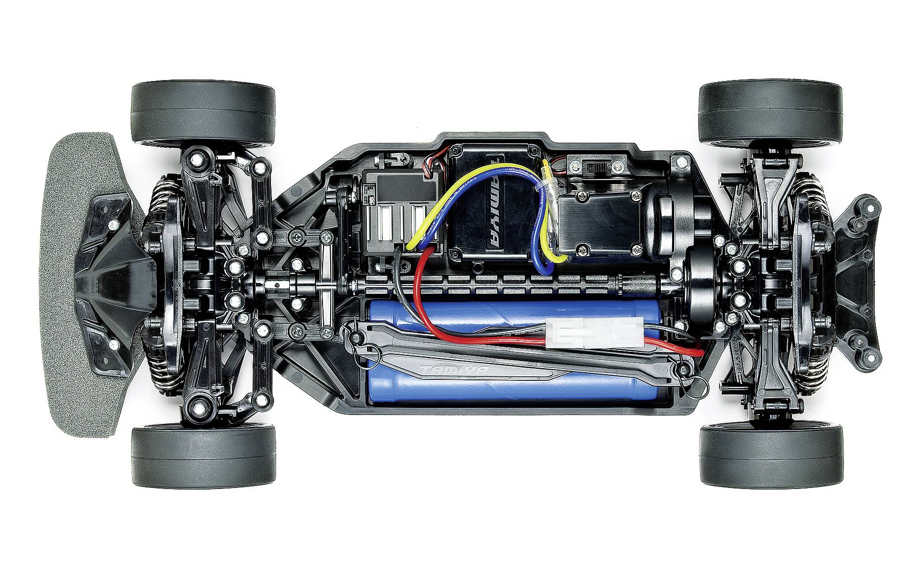 Vue d'un châssis de voiture télécommandée depuis le dessus, avec électronique, moteur, batterie et quatre roues visibles.