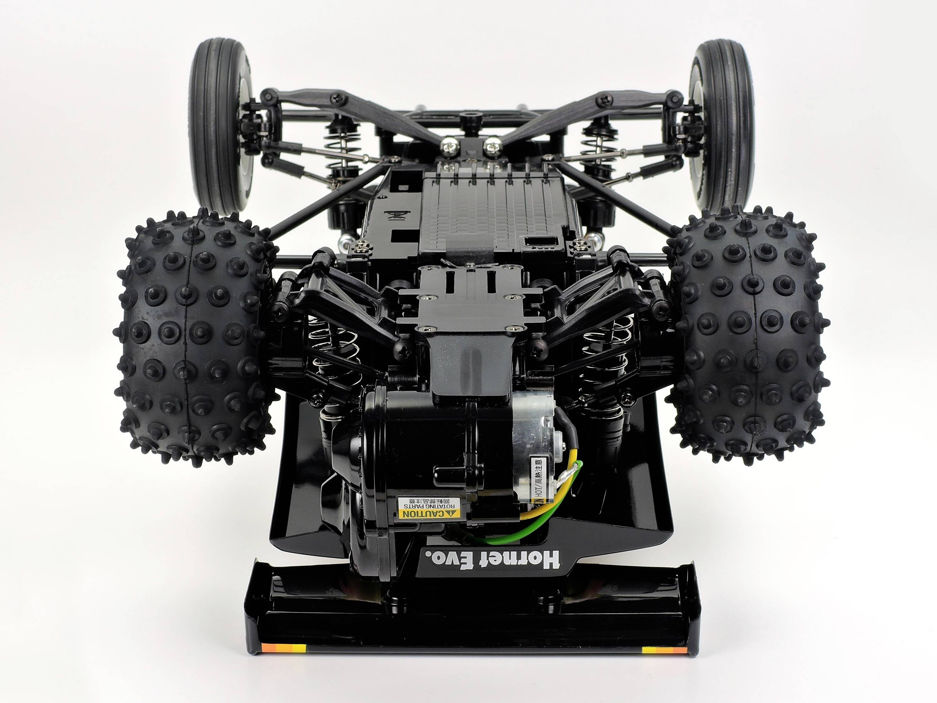 Une voiture télécommandée à l'envers, révélant sa mécanique détaillée et sa suspension de roues.