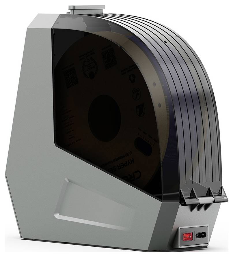 Un boîtier d'appareil avec un couvercle transparent contenant une grande bobine. L'appareil dispose d'un interrupteur en bas à droite.