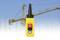 Une télécommande de grue avec des boutons devant un chantier de construction avec une grande grue jaune et une structure métallique.