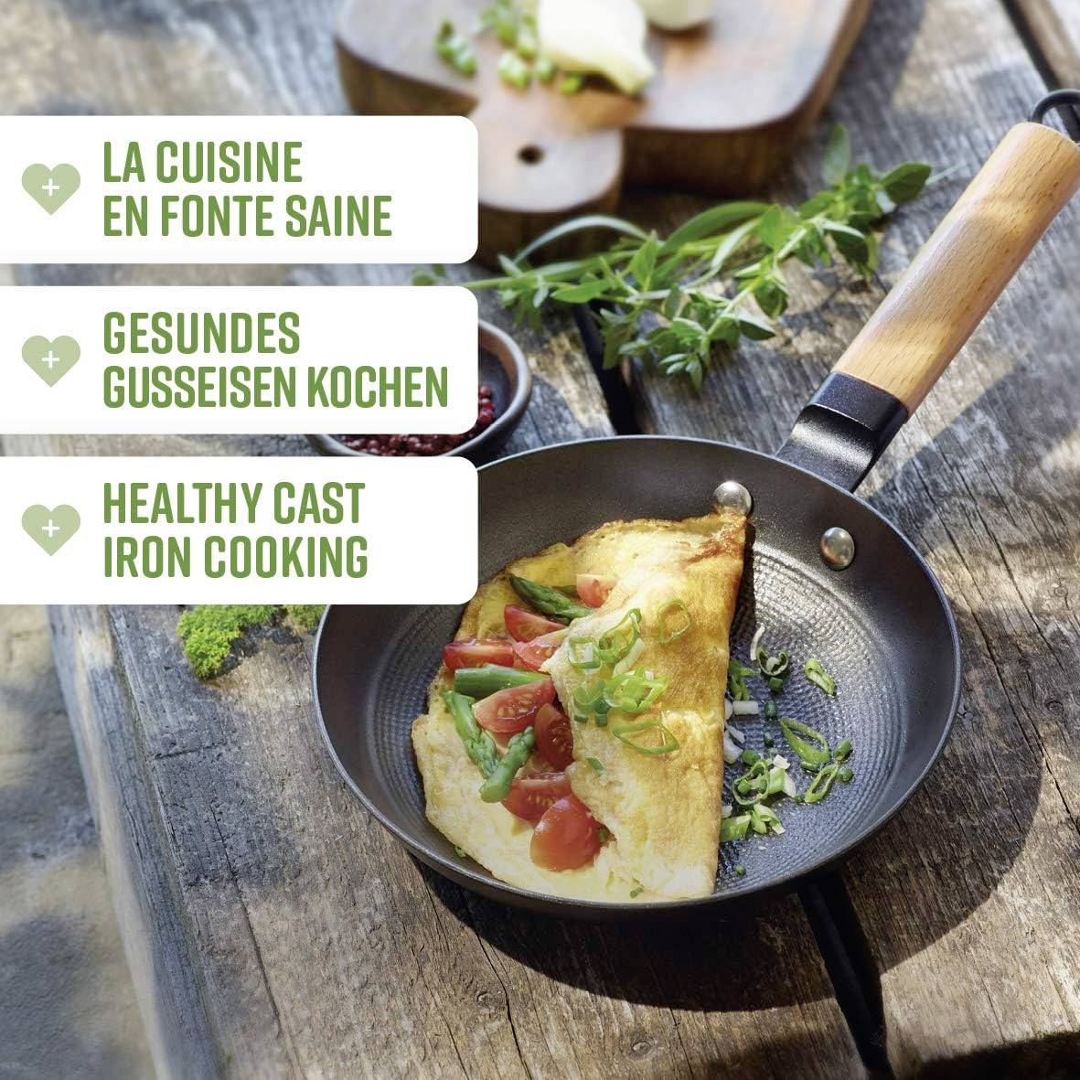 Une poêle contenant une omelette garnie de tomates, d'épinards et d'herbes. Texte décrivant la 'Cuisson Saine en Fonte' en trois langues.