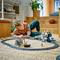 Un enfant joue avec un train électrique miniature sur un tapis rond dans un salon.