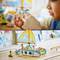 Un enfant joue avec un petit dauphin en plastique. En arrière-plan, on peut voir un bateau-jouet coloré avec des figurines.