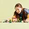 Un enfant joue avec des briques LEGO Minecraft sur un fond jaune. Il se concentre sur la construction de structures.