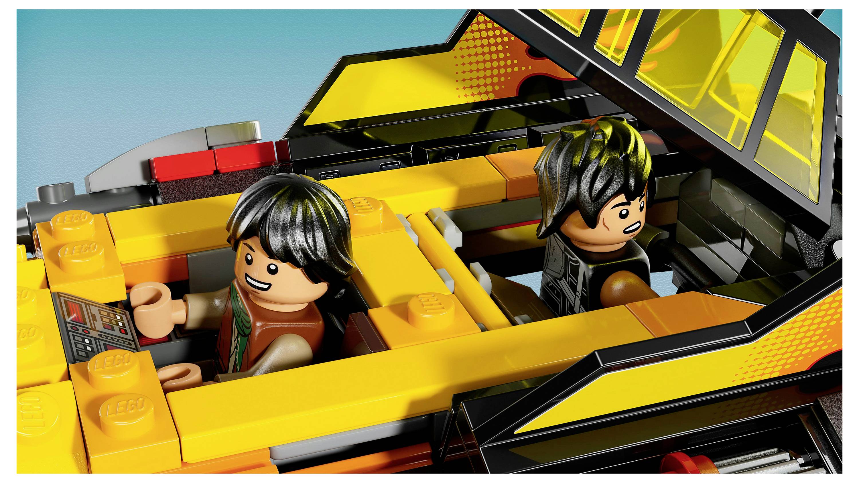Deux personnages LEGO sont assis dans une voiture LEGO jaune et noire, souriant au tableau de bord. Le toit de la voiture est partiellement ouvert.